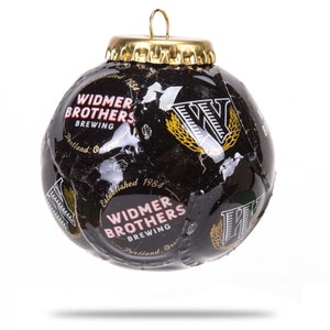 Puede incluir: Un adorno navideño negro y dorado hecho de una lata de cerveza reciclada. El adorno presenta el logotipo de Widmer Brothers Brewing y el texto "Establecido en 1984".