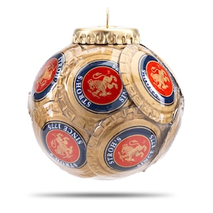May include: A unique Christmas ornament made from beer bottle caps. The ornament is spherical, with a gold-colored bottle cap top and a loop for hanging. The body is covered in gold and blue bottle caps with a red emblem and the text "STROH'S SINCE 1775".