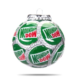 Puede incluir: Un adorno navideño verde y plateado hecho con tapas de botellas de Mountain Dew. El adorno es redondo y tiene una cuerda plateada atada a la parte superior.
