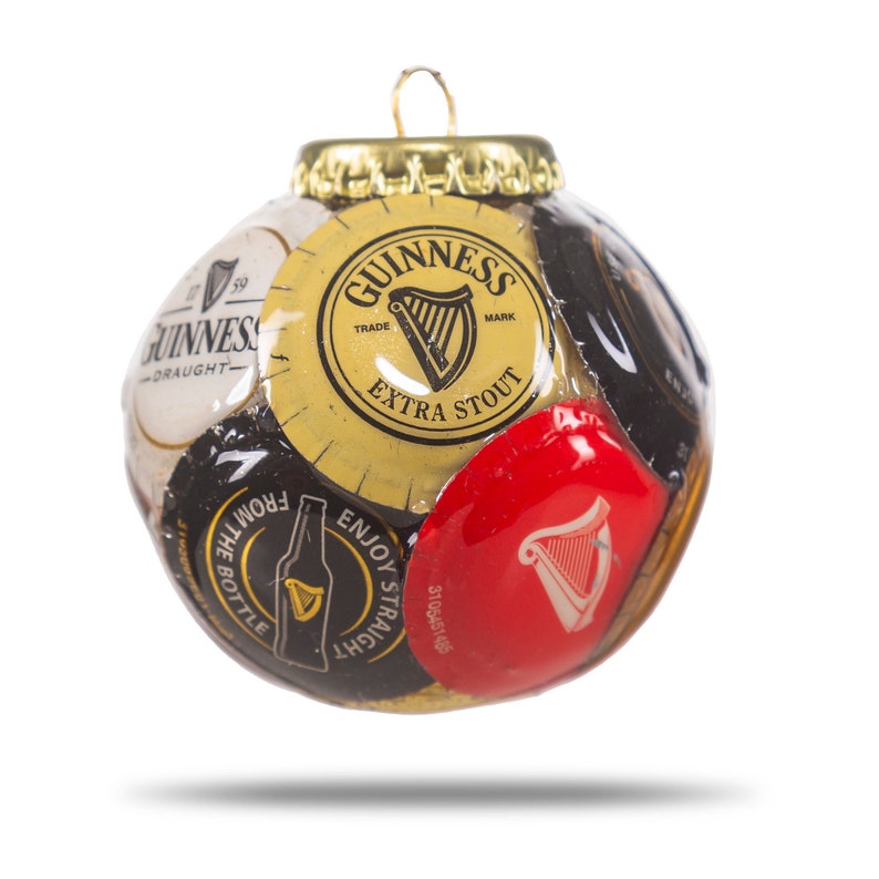 May include: A Christmas ornament made from a collection of Guinness beer bottle caps. The ornament is round and features the Guinness logo and other branding elements.