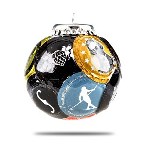 Może przedstawiać: Czarna ozdoba choinkowa wykonana z recyklingowanych zakrętek od butelek. Ozdoba jest ozdobiona r&oacute;żnymi obrazami, w tym chmielem, osobą w łodzi i twarzą osoby. Ozdoba ma srebrny wierzchołek.