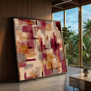 Puede incluir: Impresión artística abstracta con marco negro. La obra presenta pinceladas rectangulares y verticales en tonos burdeos, grises, beige y naranja. La pintura está apoyada contra una pared de madera en una habitación bien iluminada.