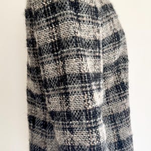 May include: A black, grey, and white plaid jacket. The jacket has a classic design with a round neckline and long sleeves. The fabric appears to be a woven tweed or similar material, offering a warm and stylish look. The jacket is a stylish garment.