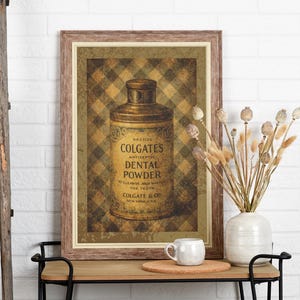 Pode incluir: Impressão vintage emoldurada com uma lata de Colgate's Dental Powder. A impressão tem uma moldura de madeira marrom e um fundo xadrez. Uma caneca branca e um vaso com flores secas estão em uma mesa pequena.