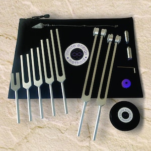 May include: A set of tuning forks in a black carrying case with the words "infinite energy method" and an infinity symbol. The set includes a variety of tuning forks, a mallet, and a small purple disc.
