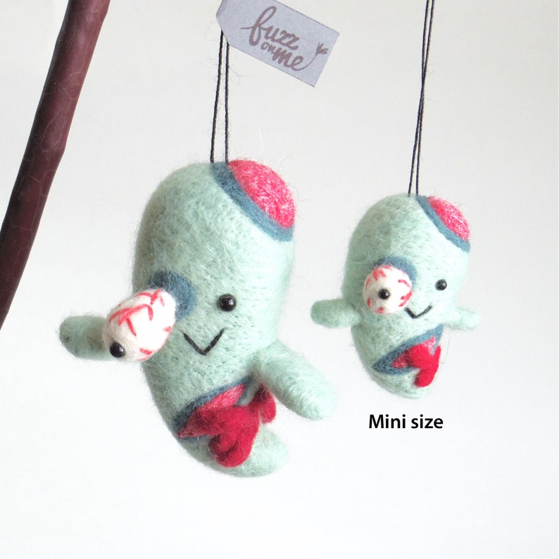 size comparison of bigger felt zombie ornament and mini version zombie ornament. mini version zombie is almost half size of the big one