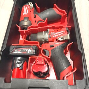 Könnte beinhalten: Ein rotes und schwarzes Milwaukee Elektrowerkzeug-Set in einem schwarzen Koffer. Das Set enthält einen Bohrer, einen Schlagschrauber, einen Akku und ein Ladegerät. Die Werkzeuge sind in einem roten Kunststoffeinsatz angeordnet.