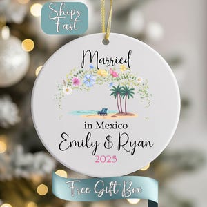 May include: White ceramic ornament with a gold ribbon for hanging. The ornament features the words "Married in Mexico" with names and a year, along with a beach scene with palm trees and flowers.
