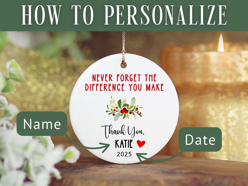 May include: White ceramic ornament with the text "NEVER FORGET THE DIFFERENCE YOU MAKE" in red. It includes a floral design and the words "Thank You, KATIE 2025". The ornament is designed to be personalized.