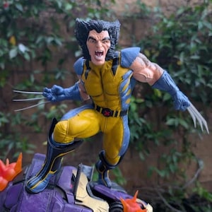 May include: A Wolverine action figure in a dynamic pose, clad in a yellow and blue costume with claws extended. The figure is atop a purple and gold structure with orange accents. The figure's face is contorted in a fierce expression.
