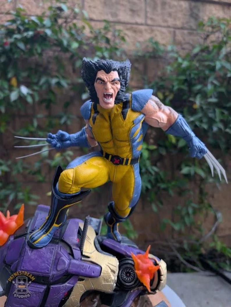 May include: A Wolverine action figure in a dynamic pose, clad in a yellow and blue costume with claws extended. The figure is atop a purple and gold structure with orange accents. The figure's face is contorted in a fierce expression.