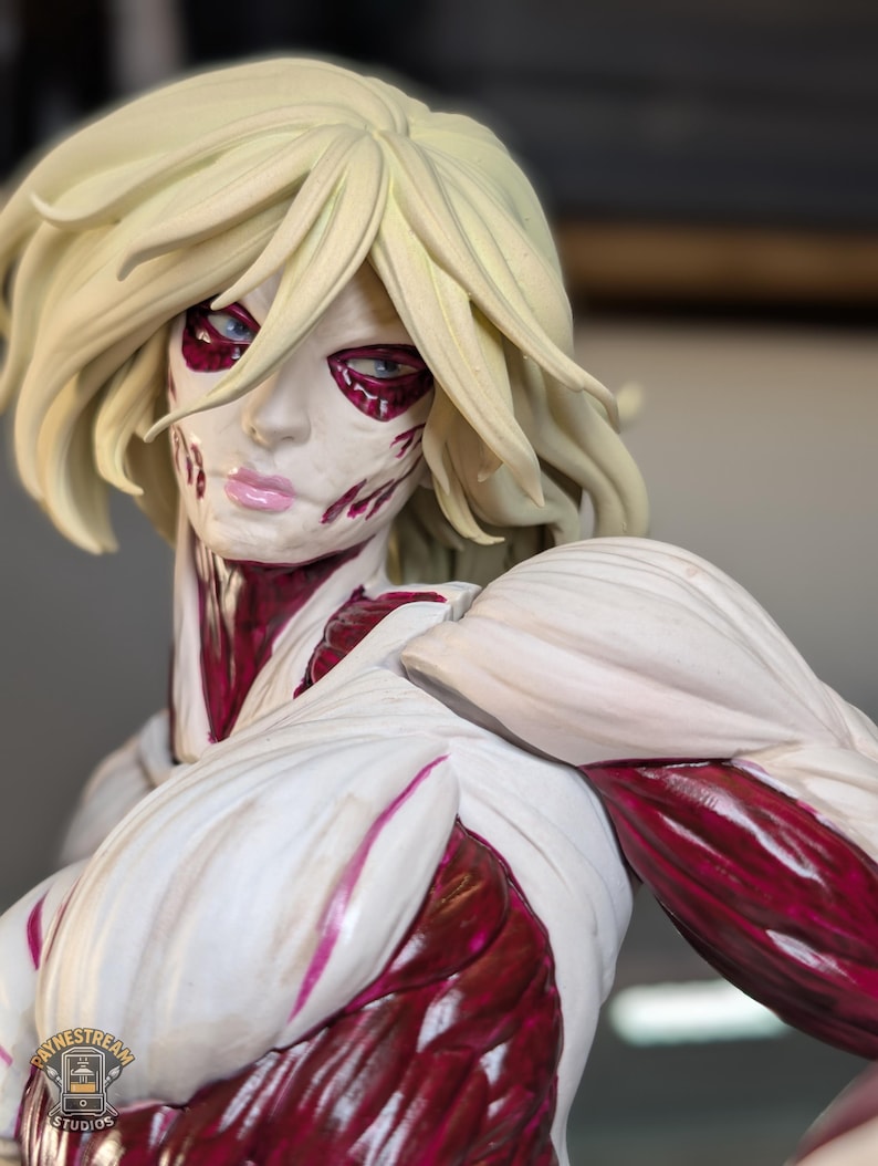 May include: A detailed figurine of a humanoid character with blonde hair, pale white skin, and exposed deep red muscle tissue. The figure features a stern facial expression with light blue eyes and pink lips, showcasing intricate anatomical textures.