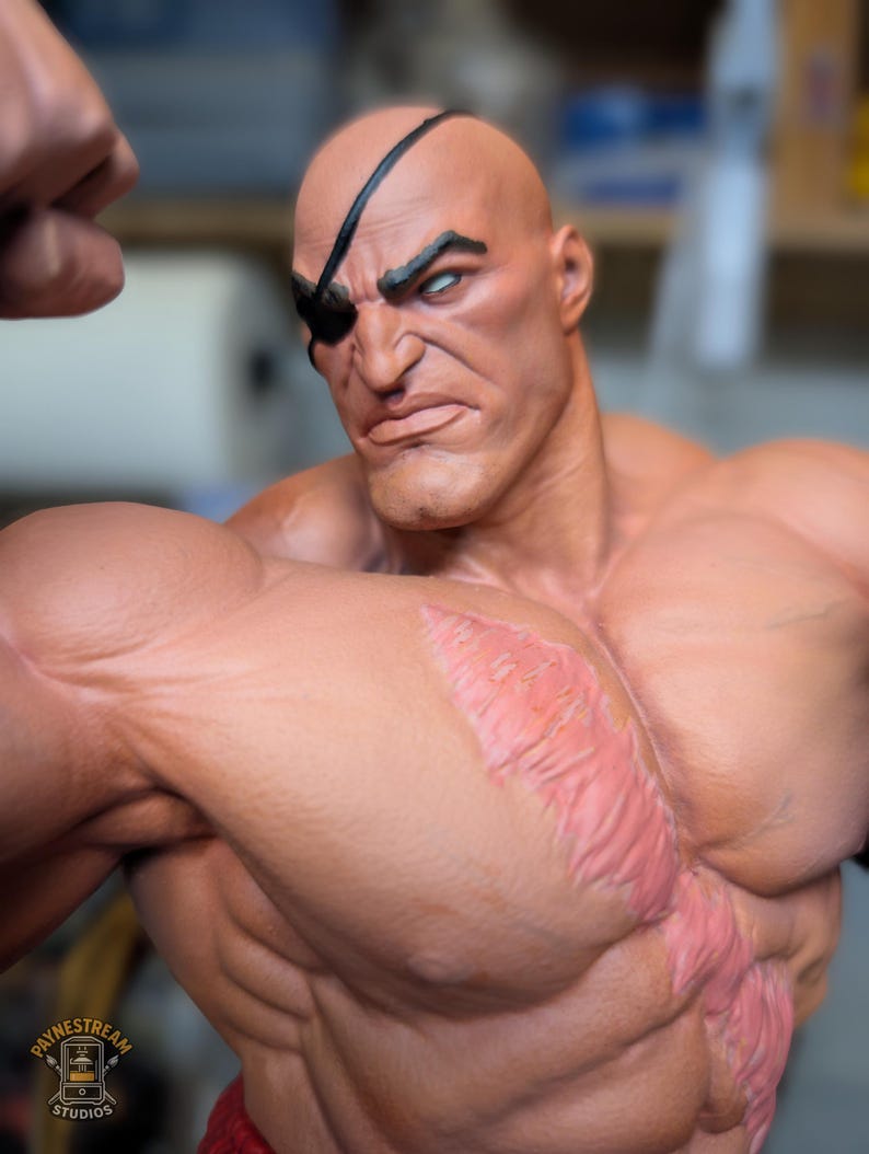 May include: A muscular, bald figurine with tan skin, a black eye patch over the left eye, and a prominent, textured pink scar running diagonally across the chest. The figure has a stern facial expression, defined musculature, and a logo reading PAYNESTREAM STUDIOS in the bottom left corner.