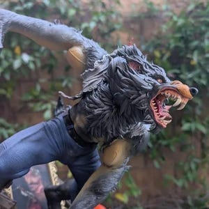 May include: A detailed figurine of a werewolf in a dynamic pose, with a snarling expression and exposed fangs. The figure has gray fur, red eyes, and is wearing blue jeans. The base of the figure has the text "PAYNESTREAM STUDIOS".