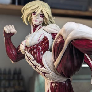 May include: A detailed figurine of a blonde character with exposed dark red muscle tissue and white connective tissue, captured in a dynamic kicking pose with a raised leg and a clenched fist. The base features a logo reading Paynestream Studios.