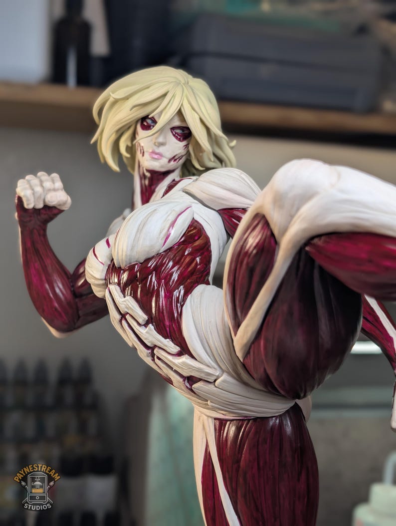 May include: A detailed figurine of a blonde character with exposed dark red muscle tissue and white connective tissue, captured in a dynamic kicking pose with a raised leg and a clenched fist. The base features a logo reading Paynestream Studios.
