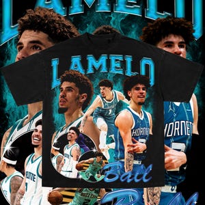 以下が含まれることがあります： バスケットボール選手のラメロ・ボールのグラフィックプリントが施された黒いTシャツ。Tシャツは青とターコイズの色合いで、「ラメロ・ボール」という文字が大きく太字で印刷されています。グラフィックプリントには、ラメロ・ボールがさまざまなバスケットボールのポーズをとっている複数の画像が含まれています。