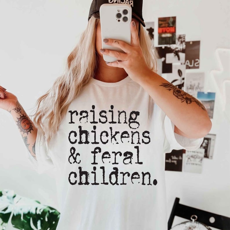 Puede incluir: Camiseta blanca con texto negro que dice "criando pollos y ni&ntilde;os salvajes."