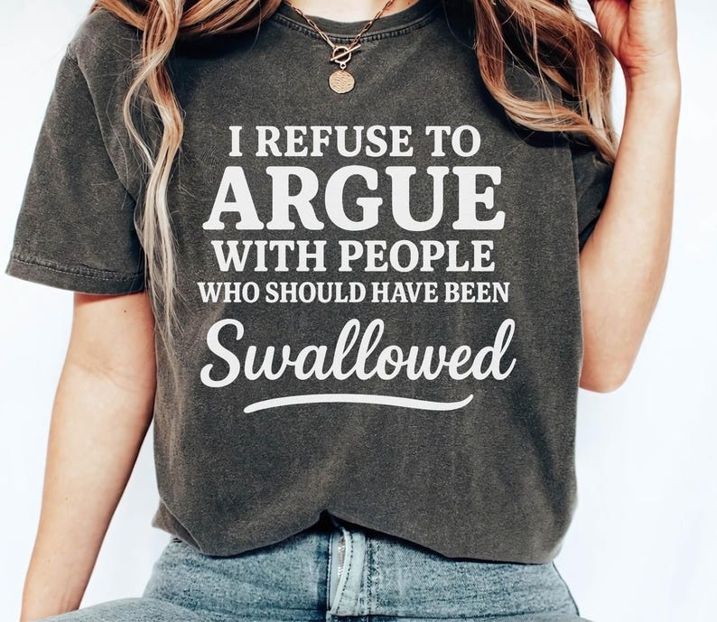K&ouml;nnte beinhalten: Dunkelgraues T-Shirt mit dem wei&szlig;en Text "I REFUSE TO ARGUE WITH PEOPLE WHO SHOULD HAVE BEEN Swallowed". Das Shirt hat einen Rundhalsausschnitt und kurze &Auml;rmel. Das Model tr&auml;gt eine blaue Jeans.