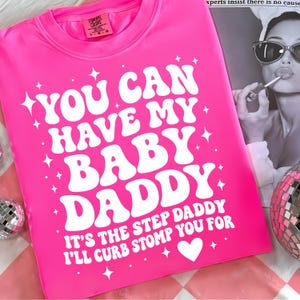 May include: Bright pink t-shirt with the text "YOU CAN HAVE MY BABY DADDY" in white, along with the phrase "IT'S THE STEP DADDY I'LL CURB STOMP YOU FOR". The shirt has a crew neck and a small Comfort Colors tag.