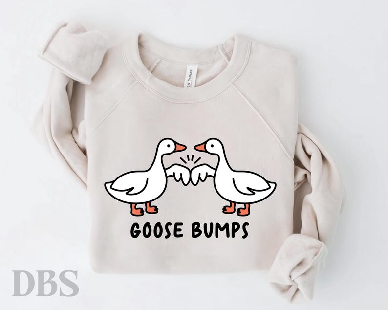 May include: A beige sweatshirt with a graphic of two geese bumping their wings together. The text "Goose Bumps" is printed below the geese.