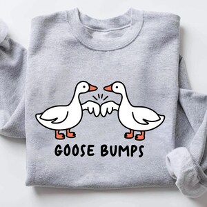 May include: A gray sweatshirt with a graphic of two cartoon geese bumping fists. The text "GOOSE BUMPS" is printed below the geese.