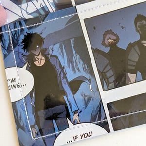May include: A wallet featuring panels from a comic book. The wallet is open, revealing interior panels with speech bubbles and action scenes. The text includes "I'm King...", "Or ten?", "Clang", "...If you", and "I'll take him."