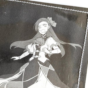 Puede incluir: Una ilustraci&oacute;n en blanco y negro de una ni&ntilde;a con el pelo largo que lleva un vestido y sostiene una espada. La ilustraci&oacute;n est&aacute; impresa en una cartera de tela negra.