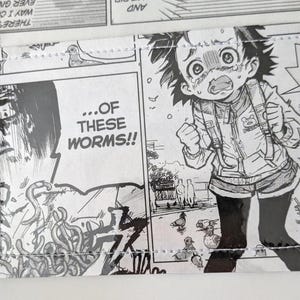 May include: Black and white manga-style print featuring panels with speech bubbles and illustrations. One panel shows a character with a shocked expression, while another reads "...OF THESE WORMS!!"