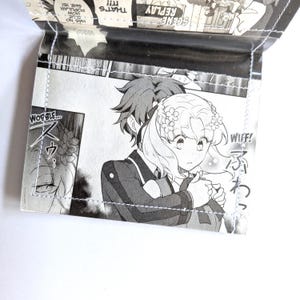 Puede incluir: Panel de manga en blanco y negro con dos personajes. El personaje masculino est&aacute; abrazando al personaje femenino. El personaje femenino tiene flores en el pelo y se sonroja. El texto del panel dice "WOBBLE..." y "WIFF!"