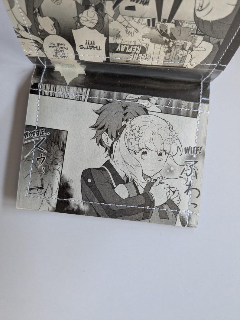 Puede incluir: Un panel de manga en blanco y negro con dos personajes. El personaje femenino tiene el pelo largo y ondulado y lleva un vestido blanco con un dise&ntilde;o floral. El personaje masculino tiene el pelo corto y puntiagudo y lleva un traje oscuro. El texto en el panel dice "WIIF!" y "WOBBLE..."