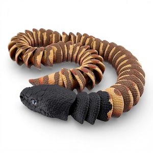 May include: A segmented articulated snake toy featuring a solid black head and neck section, transitioning into a patterned body with alternating brown and tan scales. The flexible, multi-piece design allows the snake to coil into a curved shape.