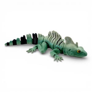 May include: A green articulated lizard figurine with a crest on its head and a long tail. The body features black striped markings along the back and tail, with yellow eyes. The segmented design allows for movement, showcasing a textured surface.
