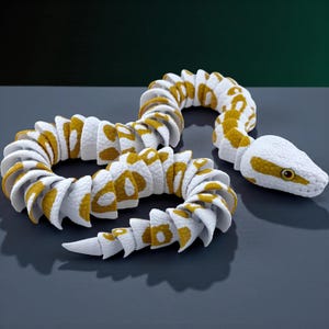 May include: A flexible, articulated toy snake featuring a white base color with textured mustard yellow patches along its segmented body. The snake has a detailed head with a visible eye and a tapered tail, constructed from multiple interlocking pieces.