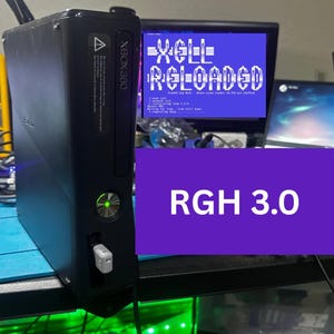 May include: A black Xbox 360 game console with a glowing green power button and a small white USB drive inserted in the front port. A monitor in the background displays the text XELL RELOADED and RGH 3.0 in white against a blue background.