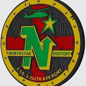 May include: A circular emblem with a black, wood-grain background, a red cross, and a large green "N" with an upward arrow. The emblem features a green helicopter, a yellow star, and the words "NORTHSTAR" and "DUSTOFF". The text "C CO. 2-211TH AVN RGMT" is also present.