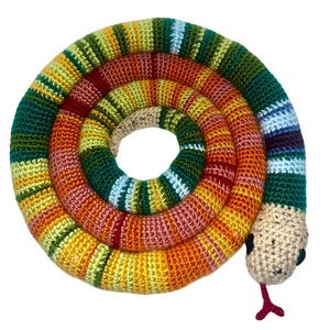 Peut inclure: Un jouet serpent en crochet coloré avec un corps rayé et une tête beige. Le serpent est enroulé en cercle.
