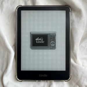 Puede incluir: Lector de libros electrónicos Kindle negro con una funda protectora transparente. La pantalla muestra un gráfico de cámara digital con el texto "alexis's kindle". La palabra "kindle" está impresa en la parte inferior del dispositivo.