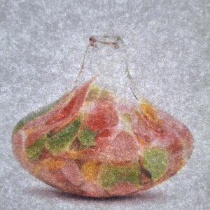 Op de afbeelding: Een heldere glazen fles gevuld met kleurrijke snoepjes. De snoepjes hebben verschillende vormen en maten, met rode, groene en gele tinten. De fles heeft een afgeronde basis en een smalle hals.