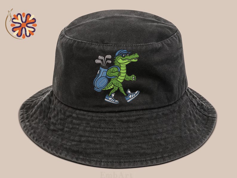 May include: Black bucket hat with a green alligator graphic wearing sunglasses and carrying a golf bag. The alligator is wearing sneakers. The hat is made of a washed, textured fabric.