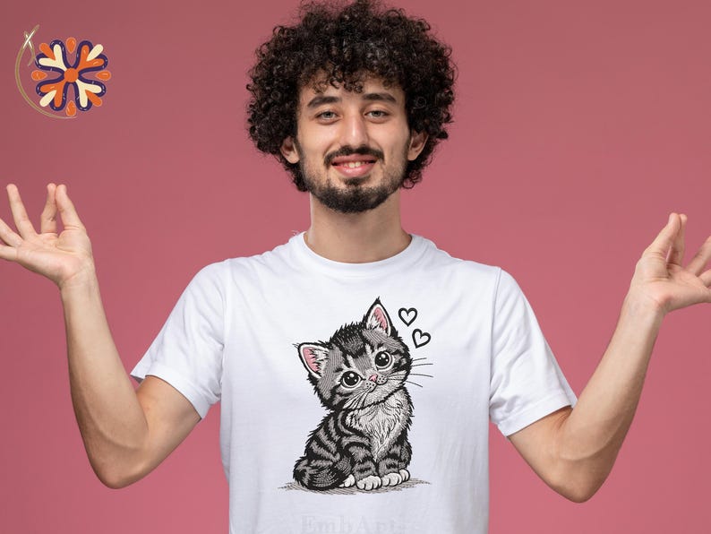 May include: White t-shirt with a detailed illustration of a grey and black tabby kitten with large eyes and two hearts. The kitten is sitting, and the design is centered on the shirt.