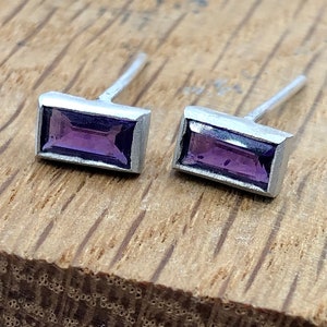 May include: A pair of silver stud earrings with rectangular purple gemstones.