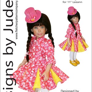 以下が含まれることがあります： 28cm の人形用のピンクと黄色の花柄のドレス。ドレスは白いボタン留めのボディスと、ピンクの花柄のアクセントがついた黄色のスカート。人形は白いタイツと黄色の靴を履いています。ドレスはタマラ・ケイシーがデザインしたもので、「フlirty」と呼ばれています。