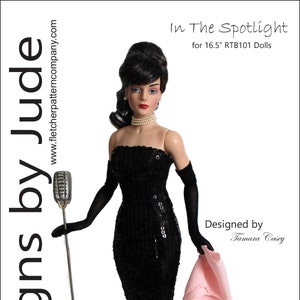 May include: A black sequined dress with a tulle skirt and a pink shawl. The dress is designed for 16.5 inch dolls. The text "In The Spotlight" and "Designed by Tamara Casey" is included in the image.