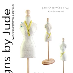 May include: A 15.5 inch fabric dress form with a wooden base. The form is made of white fabric and has a yellow measuring tape around it. The form is designed by Tamara Casey.