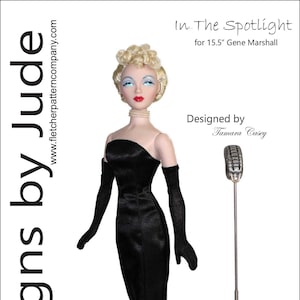 May include: A black and white illustration of a doll wearing a black dress and a black tulle skirt. The doll is standing next to a microphone on a stand. The text "In The Spotlight" and "Designed by Tamara Casey" is visible in the image.