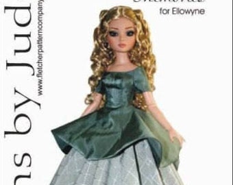 Puede incluir: Muñeca con un vestido verde con falda amplia, sobre fondo blanco. La muñeca tiene cabello rubio rizado. El texto incluye "Designs by Jude" y "Memories for Ellowyne". La dirección del sitio web también es visible.