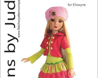 Pode incluir: Uma boneca usando um gorro rosa, uma jaqueta vermelha com estrelas douradas, uma saia de camadas verde e rosa e sapatos rosa. A boneca está em pé em um fundo branco. O texto "Clever Girl for Ellowyne" está escrito acima da boneca. O texto "Designed By Tamara Casey" está escrito abaixo da boneca.