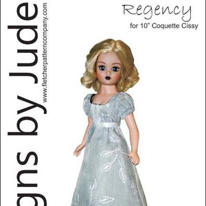 May include: A Regency-style dress pattern for a 10-inch Coquette Cissy doll. The pattern is printed on white paper with black text and a photo of a doll wearing the dress. The dress is a light blue color with a white trim and a green underskirt.