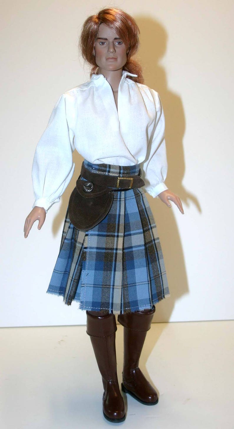May include: A doll wearing a white shirt, a brown leather belt, a blue and brown plaid kilt, and brown boots.